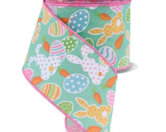 May include: A roll of Easter-themed ribbon with a light green background. The pattern includes Easter eggs, carrots, and bunnies. The ribbon is trimmed with a pink edge.