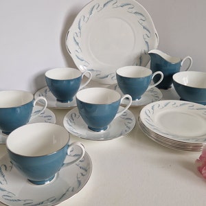 Op de afbeelding: Een vintage theeservies met een blauw en wit bloemenpatroon. De set bevat een theepot, een roomkan, een suikerpot, zes theekopjes en zes schoteltjes.