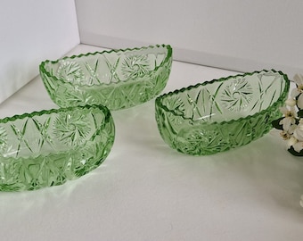 May include: Three green glass bowls with a cut glass design. The bowls are oval shaped and have a scalloped edge.