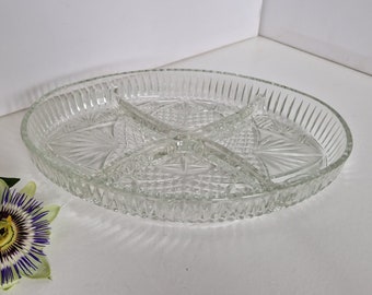 May include: A clear glass serving dish with four divided sections. The dish has a decorative, cut-glass pattern.