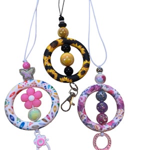 May include: Three colorful beaded lanyards with a ring and a clip. The lanyards feature a sunflower, floral, and geometric design. $10.