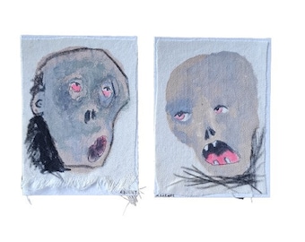 May include: Two hand-painted portraits on fabric, each depicting a pale blue-grey face with pink eyes and a wide open mouth. The face on the left has a dark grey outline around the head and neck. The face on the right has a dark grey outline around the bottom of the face.