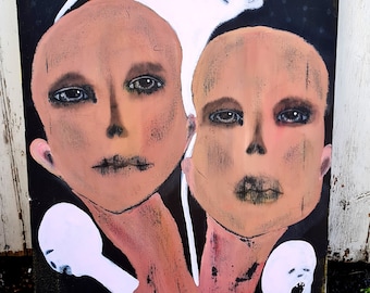 Puede incluir: Una pintura de dos caras con una figura fantasmal blanca sobre ellas. Las caras están pintadas en tonos marrones y rosados, con ojos y labios negros. El fondo es negro con puntos blancos.