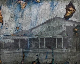 May include: A vintage black and white photograph of a building with a large, flat roof. The building has a porch with columns and a series of windows. The photo is faded and has a blue and green paint overlay.