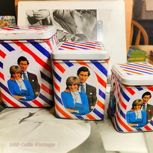 Peut inclure: Ensemble de trois boîtes métalliques vintage. Elles présentent un motif à rayures rouges, blanches et bleues et un portrait d'un couple. Les boîtes sont de tailles variées avec des couvercles blancs.