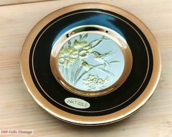 Könnte beinhalten: Eine dekorative Platte mit goldenem Rand, schwarzem Band und einem zentralen Design mit einem Kolibri und Blumen. Die Platte ist mit "24KT GOLD" beschriftet.