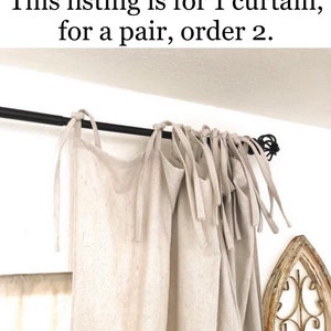 May include: A pair of off-white linen curtains with a simple tie-top design. The curtains are hung on a black rod and are gathered at the top. The text "This listing is for 1 curtain, for a pair, order 2." is visible at the top of the image.