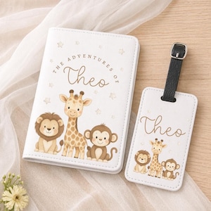 May include: White passport holder and luggage tag with a lion, giraffe, and monkey design. The passport holder says "The Adventures of Theo" and the luggage tag says "Theo". Both have a black leather strap.