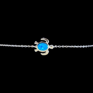 Può includere: Un braccialetto a catena d'argento con un ciondolo a forma di tartaruga in opale blu.