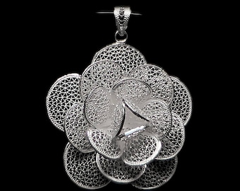 May include: A silver filigree flower pendant with a delicate, intricate design. The pendant is made of fine silver wire and has a circular shape.
