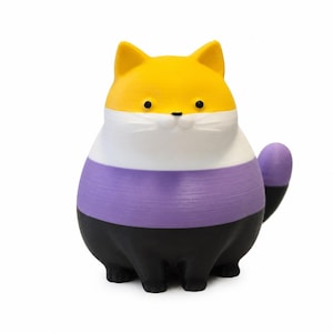 Puede incluir: Una pequeña figura de gato redondeada con rayas horizontales amarillas, blancas, moradas y negras. El gato tiene ojos negros pequeños, una nariz negra diminuta y una cola corta. La superficie muestra una textura impresa en 3D en todo el cuerpo.