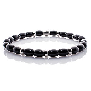 Op de afbeelding: Zwarte kralen armband met zilveren accenten. De armband is gemaakt van ovale zwarte kralen en zilveren tussenkralen.