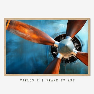 Puede incluir: Primer plano de una hélice de avión vintage con palas de madera marrón y una carcasa de motor de metal azul. La hélice se coloca sobre un fondo azul.
