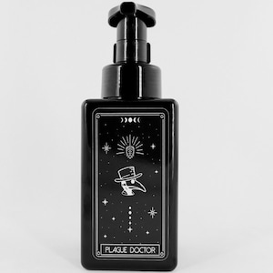 May include: Black rectangular bottle with a pump dispenser. The front features a white graphic of a plague doctor, stars, and the text "PLAGUE DOCTOR". The bottle has a glossy finish and is set against a white background.