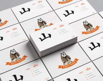 Könnte beinhalten: Ein Stapel weißer Visitenkarten mit einer Schwarzweißillustration eines Berges und dem Wort "shan" in Schwarz. Das Wort "shan" ist im Englischen als "Berg" definiert. Die Karten zeigen auch einen Cartoon-Panda, der eine braune Jacke und ein rotes Bandana trägt. Der Panda hält ein rotes Banner mit den Worten "Kong Teach" in Schwarz.