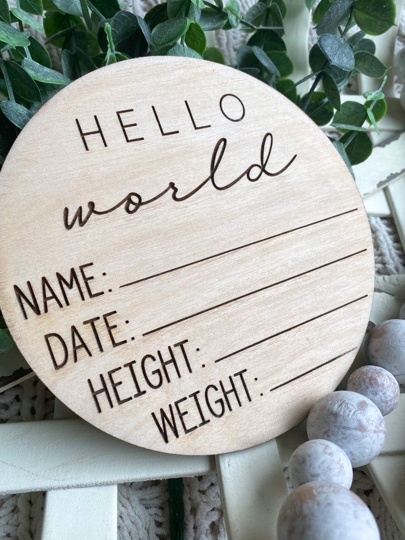 May include: A round wooden sign with the text "HELLO world" and blank lines for "NAME", "DATE", "HEIGHT", and "WEIGHT".