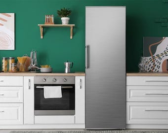 Puede incluir: Una cocina moderna con gabinetes blancos, un horno de acero inoxidable y un refrigerador grande. Una estantería de madera alberga plantas y objetos decorativos. La pared verde proporciona un telón de fondo vibrante.
