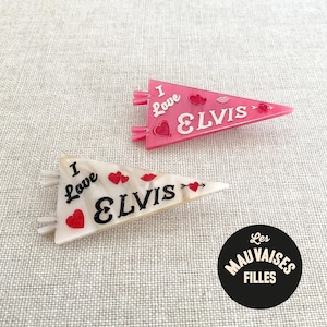 Può includere: Due fermagli per capelli a forma di gagliardetto con la scritta "I Love Elvis". Uno è rosa con scritte e cuori bianchi, l'altro è bianco con scritte nere e cuori rossi. I fermagli sono accessori.