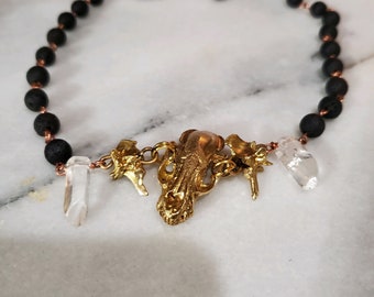 Brass ferret skull and snake vertebrae strung with lava beads with quartz point accents.