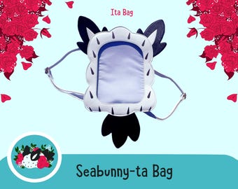 May include: A white and black sea bunny-shaped ita bag with a clear plastic window. The bag has a black strap and the text "Seabunny-ta Bag" is printed on the bottom of the image.