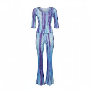 Puede incluir: Conjunto de dos piezas con top de cuello redondo y mangas tres cuartos y pantalón acampanado. El conjunto presenta rayas verticales azules y moradas. La tela tiene un aspecto sutilmente texturizado, creando un efecto brillante.