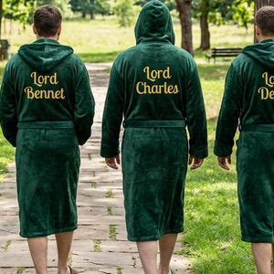 May include: Four people wearing dark green hooded robes with gold embroidered names: Lord Arthur, Lord Bennet, Lord Charles, and Lord Derek. They are walking on a stone path in a park, surrounded by trees and greenery.