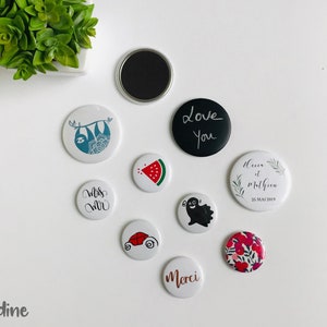 Peut inclure: Assortiment de badges ronds, blancs et noirs avec différents motifs. Les motifs comprennent un paresseux, une pastèque, une voiture, un fantôme, un motif floral, les mots "Love You", "Miss Mr", "Merci", et "Heure et Mathieu 25 Mai 2019".