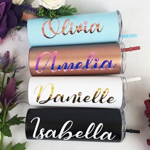 K&ouml;nnte beinhalten: Vier personalisierte Edelstahlbecher mit den Namen Olivia, Amelia, Danielle und Isabella in einer kursiven Schrift. Die Becher sind in verschiedenen Farben: hellblau, kupfer, wei&szlig; und schwarz. Jeder Becher hat einen Strohhalm.