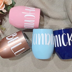 May include: Four personalized stainless steel tumblers with different names on each. The tumblers are in pink, rose gold, light blue, and navy blue.