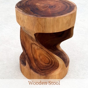 May include: A wooden stool with a unique twisted design. The stool is made of natural wood with a rich brown colour. It measures 455mm in height and 350mm in width.
