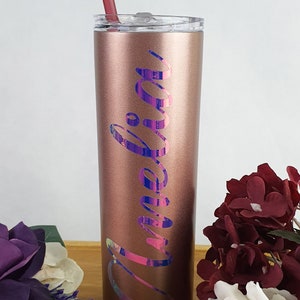 K&ouml;nnte beinhalten: Ein ros&eacute;goldener Edelstahlbecher mit einem regenbogenfarbenen Vinyl-Aufkleber, auf dem "Amelia" steht. Der Becher hat einen durchsichtigen Deckel und einen rosa Strohhalm.
