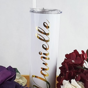 K&ouml;nnte beinhalten: Ein wei&szlig;er Edelstahlbecher mit dem goldenen Vinylnamen "Danielle" an der Seite. Der Becher hat einen durchsichtigen Deckel und einen wei&szlig;en Strohhalm.