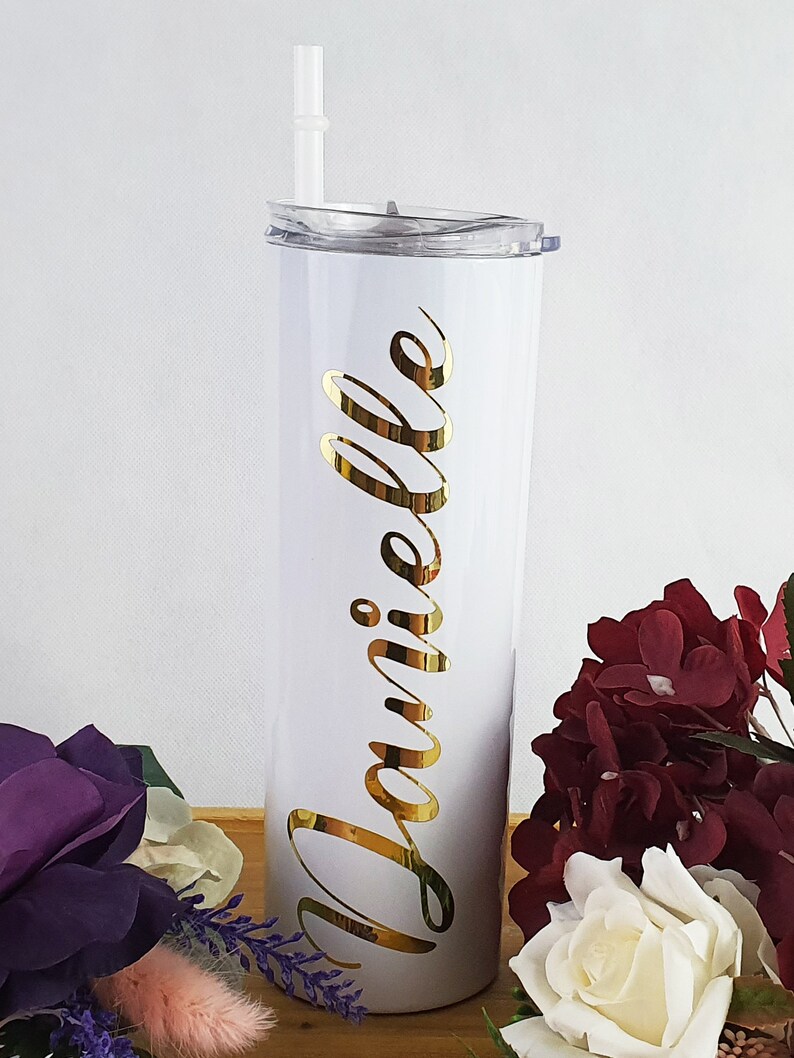 K&ouml;nnte beinhalten: Ein wei&szlig;er Edelstahlbecher mit dem goldenen Vinylnamen "Danielle" an der Seite. Der Becher hat einen durchsichtigen Deckel und einen wei&szlig;en Strohhalm.