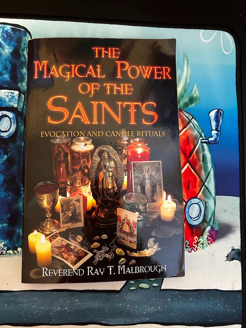 May include: A book titled "The Magical Power of the Saints" with the subtitle "Evocation and Candle Rituals." The cover features candles, religious statues, and images. The author's name, Reverend Ray T. Malbrough, is at the bottom.