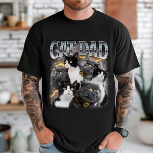 May include: Black t-shirt with the text "CAT DAD" in a silver and white font. The graphic features six cats with various fur patterns, some wearing bow ties, set against a background of lightning.