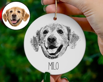 May include: A white ceramic ornament with a black and white sketch of a golden retriever dog's head. The dog is smiling and the ornament has the name "MILO" written below the dog's head.