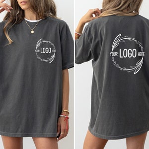 May include: A charcoal gray oversized t-shirt with a white floral design and the text "YOUR LOGO HERE" on the front and back.