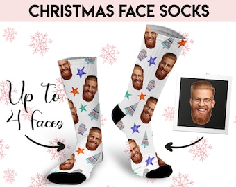 May include: A pair of white Christmas socks with a festive design featuring colorful Christmas trees, stars, and mittens. The socks are personalized with multiple faces, up to four, making them a unique and fun gift.