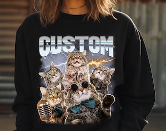 May include: Black sweatshirt featuring a graphic of five cats with sunglasses, bow ties, and a microphone, set against a backdrop of lightning. The word "CUSTOM" is displayed above the cats in a stylized font.