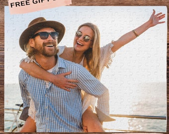 Peut inclure: Un couple profite d'une journée en bateau. La femme porte une robe blanche et des lunettes de soleil, et l'homme porte une chemise à carreaux bleu et blanc, un chapeau marron et des lunettes de soleil. Ils sourient et rient tous les deux.