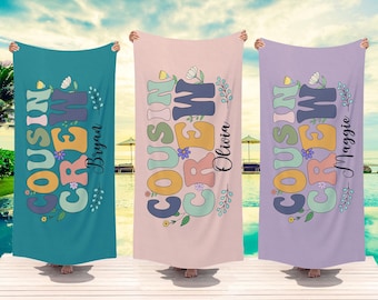 May include: Three beach towels with the text "Cousin Crew" in colorful letters with floral accents. The towels are turquoise, pink, and purple. The names "Brynn", "Olivia", and "Maggie" are written on the towels.