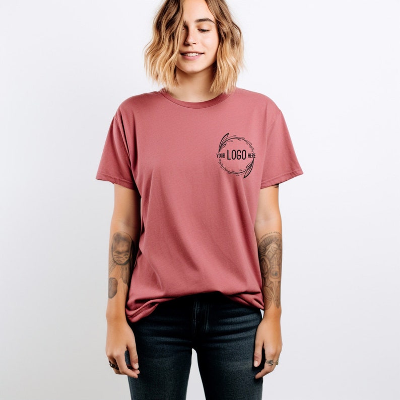 May include: A mauve t-shirt with short sleeves and a round floral design on the front. The design includes the text "YOUR LOGO HERE".