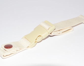 May include: Off-white canvas strap with a beige plastic buckle and a brown button. The strap is folded over itself and has a woven texture. The buckle is in the centre of the strap.