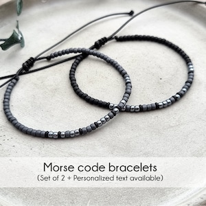 May include: Two gray and black beaded bracelets with adjustable string closures. Morse code bracelets (Set of 2 + Personalized text available).