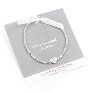 Braccialetto stretch cuore - Tutto ciò di cui hai bisogno è l'amore! Un braccialetto elasticizzato sulla carta regalo con area messaggi stampata