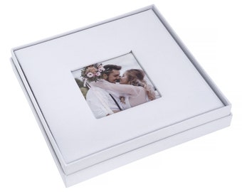 May include: White photo album with a square window showing a couple kissing. The album is closed and has a white background.
