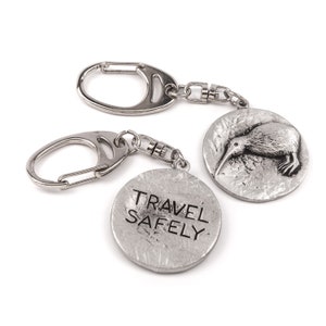 May include: Silver keyring with a kiwi bird charm and a round tag that says "TRAVEL SAFELY".
