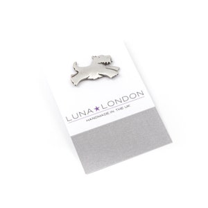 May include: A silver metal pin shaped like a Scottish Terrier dog. The pin is on a white card with the text "LUNA★LONDON HANDMADE IN THE UK".