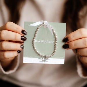 Best Big Sister - Braccialetto elastico a forma di cuore su un morbido nastro color salvia legato con carta regalo con area messaggio stampata sul retro (taglia unica)