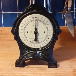 May include: A vintage black kitchen scale with a brass bowl. The dial shows measurements up to 900, with the text "Max 3kg". The scale is a classic kitchen tool, likely from the early to mid-20th century.